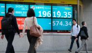 Pedestrians walk in front of a quotation board displaying share prices of the Tokyo Stock Exchange in Tokyo on May 1, 2020. Tokyo stocks closed down more than two percent on May 1 as concerns grew over tensions between the US and China, with traders remai