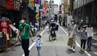 TOPSHOT - People walk past shops in a residential area in Tokyo on May 4, 2020. / AFP / CHARLY TRIBALLEAU
