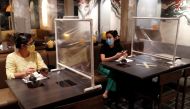 Women are seen at a Taiwanese hot pot style restaurant that reopened after the easing of restrictions with the implementation of a plastic barrier and social distancing measures to prevent the spread of the coronavirus disease (COVID-19) in Bangkok, Thail
