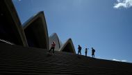 A handful of tourists stand atop the mostly deserted steps of the Sydney Opera House, where scheduled public performances have been cancelled due to the coronavirus disease (COVID-19), in Sydney, Australia, March 18, 2020. REUTERS/Loren Elliott/File Photo