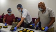 Moldovan tennis player Dmitrii Baskov (C) packs food to be distributed to people in need along with Director of Ace Tennis Academy Pramesh Modi (R) and Founder of Shree Sava Foundation Ami Pramesh Modi during nationwide lockdown as a preventive measure ag
