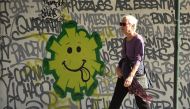 A woman walks past a street art in Sydney on May 8, 2020. Australia's government unveiled a three-stage plan to get the economy back to a new 