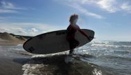 A surfer walks into the water as Italy begins to ease some of the restrictions of the coronavirus disease (COVID-19) lockdown, in Castiglione della Pescaia, Italy May 9, 2020. REUTERS/Jennifer Lorenzini