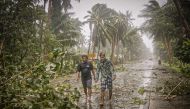 Residents brave rains and strong wind as they walk past uprooted trees along a highway in Can-avid town, Eastern Samar province, central Philippines on May 14, 2020, as Typhoon Vongfong makes landfall. / AFP / Alren BERONIO
