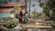 Residents stand amongst debris and next to a huge crucifix blown from the church after it was destroyed at the height of typhoon Vongfong in Arteche town, Eastern Samar province on May 15, 2020, a day after the typhoon hit the town. typhoon Vongfong has d