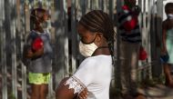 Children wait in lines at a crèche in Langa, near Cape Town on May 14, 2020, to receive a meal, which will include soup made by Woodstock Breweries, which is part of a project to feed people made vulnerable under the lockdown in South Africa, as a result 