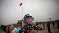 :A woman holds a child who wears a protective face cover as they pose for pictures near a Chinese national flag at the Tiananmen Square in Beijing, following the novel coronavirus disease (COVID-19) outbreak, China May 16, 2020. REUTERS/Tingshu Wang
