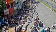 Migrant workers and their families wait for transport to reach to a railway station to board a train to their home state of northern Uttar Pradesh, after a limited reopening of India's giant rail network following a nearly seven-week lockdown to slow the 