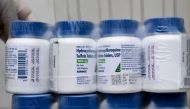 :(FILES) In this file photo taken on April 21, 2020 a Salvadoran Health Ministry worker shows a package of bottles of HydroxyChloroquine pills to be distributed in hospitals in San Salvador, amid the COVID-19 coronavirus outbreak.  / AFP / Yuri CORTEZ

