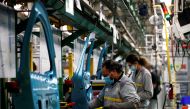 Employees, wearing protective face masks, work on the automobile assembly line of Renault ZOE cars at the Renault automobile factory in Flins as the French carmaker ramps up car production with new security and health measures during the outbreak of the c
