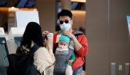 FILE PHOTO: A woman wearing a mask to avoid the spread of the coronavirus disease (COVID-19) takes a photograph of her husband and child after checking in at Gimpo international airport in Seoul, South Korea, May 1, 2020. REUTERS/Kim Hong-Ji/File Photo
