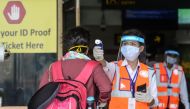 An airport employee (C) wearing a face shield checks the body temperature of a passenger at Bagdogra airport after the goverment eased a nationwide lockdown imposed as a preventive measure against the COVID-19 coronavirus, on the outskirts of Siliguri on 