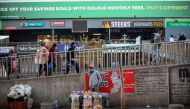 An informal vendor sets up his stall while commuters wearing face masks as a preventive measure against the spread of the COVID-19 coronavirus arrive at the Bara taxi rank in Soweto, Johannesburg, on June 1, 2020. / AFP / Michele Spatari
