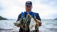 In this photo taken on May 13, 2020, Gary Stokes, founder of the environmental group Oceans Asia, poses with discarded face masks he found on a beach in the residential area of Discovery Bay on the outlying Lantau island in Hong Kong.  / AFP / Anthony WAL