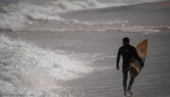 A surfer walks at the Arpoador beach in Rio de Janeiro state, Brazil, on June 02, 2020, during the new coronavirus COVID-19 pandemic. / AFP / MAURO PIMENTEL
