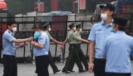 Paramilitary police officers (C) march as police stand guard at the entrance to the closed Xinfadi market in Beijing on June 13, 2020. AFP / GREG BAKER