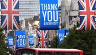 A bus is seen passing underneath Union Jack flags and banners with a message reading 