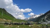 Indian army soldiers walk past their parked trucks at a makeshift transit camp before heading to Ladakh, near Baltal, southeast of Srinagar, June 16, 2020. REUTERS/Stringer
