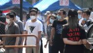 People wearing face masks wait to take a swab test for the COVID-19 coronavirus as officials conduct mass testing following a new cluster of cases last week, in Beijing on June 18, 2020. Beijing reported another 21 cases of the coronavirus on June 18, as 