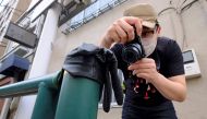 This picture taken on May 25, 2020 shows Japanese photographer Koji Ishii taking pictures of a lost glove on a pole beside the road in Tokyo. AFP / Kazuhiro Nogi 