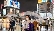 Pedestrians walk with umbrellas as evening rain falls in Tokyo on June 19, 2020. / AFP / CHARLY TRIBALLEAU