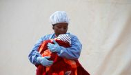 Rachel Kahindo, an Ebola survivor working as a caregiver to babies who are confirmed Ebola cases, holds an infant outside the red zone at the Ebola treatment centre in Butembo, Democratic Republic of Congo, March 25, 2019. REUTERS/Baz Ratner/File Photo