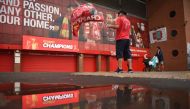 A fan waves a flag outside Anfield stadium in Liverpool, north-west England on June 26, 2020 after Liverpool sealed the Premier League title the previous evening.   AFP / Oli SCARFF
