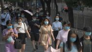 People wear masks as they walk to work in Beijing on June 28, 2020. Beijing has partially lifted weeks-long lockdown imposed in the Chinese capital to head off a feared second wave of coronavirus infections after three million samples were taken in two we