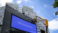 Workers paste portraits of healthcare workers on the facade of the Opera Bastille, at the initiative of the collective #ProtegeTonSoignant to pay tribute to caregivers in first ligne during the Covid-19 epidemic, next to a screen reading 