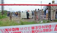 Policemen stand guard next to an overturned vehicle after the gangster Vikas Dubey was shot dead by police, on a highway at Sachendi in Uttar Pradesh state on July 10, 2020. / AFP / 