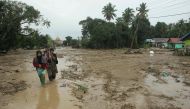 Villagers walk through a flooded area in Radda village in North Luwu regency, South Sulawesi on July 14, 2020, after three rivers overflowed due to torrential rains. AFP / Aryanto