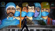 A man walks past a mural of frontline workers after the government eased a nationwide lockdown imposed as a preventive measure against the COVID-19 coronavirus in New Delhi on July 14, 2020. / AFP / Sajjad HUSSAIN