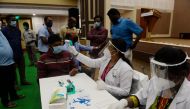 A medical technician (C) takes the body temperature of a man before taking a sample for a COVID-19 anti-body tests at a temporary testing facility for frontline workers during a lockdown as a preventive measure against the COVID-19 coronavirus in Chennai 