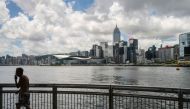 A man walks on a pier in Victoria Harbour past a view of commercial buildings in Hong Kong on July 16, 2020. / AFP / Anthony WALLACE / 