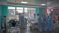 In this photograph taken on July 15, 2020 doctors and nurses wearing Personal Protective Equipment (PPE) gather next to a COVID-19 coronavirus patient at the Intensive Care Unit of the Sharda Hospital, in Greater Noida./ AFP / XAVIER GALIANA
