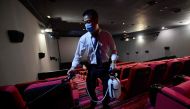 A worker disinfects a cinema in Beijing on July 20, 2020. Hundreds of cinemas reopened in scores of Chinese cities on July 20 following a nearly six-month nationwide shutdown due to the coronavirus. AFP / GREG BAKER