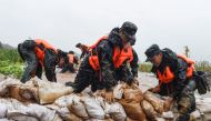 This photo taken on July 15, 2020 shows China's paramilitary police officers placing sandbags on a levee in the rain near the Yangtze River in Tongling in China's eastern Anhui province. The vast Yangtze drainage area has been lashed by torrential rains s