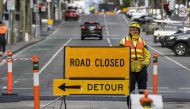 A worker stands besides a road sign in Melbourne on July 21, 2020. AFP / William West 
