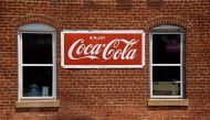 In this file photo a Coca Cola sign is seen in front of a store in Amherst, Virginia on May 9, 2020. Coca-Cola reported a steep drop in second-quarter profits on July 21, 2020 due to a big decline in away-from-home consumption, especially at the height of