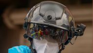 A volunteer health worker of the Non-Governmental Organization (NGO) Bharatiya Jain Sanghatana (BJS) wearing Personal Protective Equipment (PPE) looks through a smart helmet equipped with a thermo-scan sensor to check the body temperature during a door-to