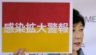 This picture taken on July 15, 2020 shows Tokyo Governor Yuriko Koike displaying a sign reading 'Infection spread alert' during a press conference at the Tokyo Metropolitan Government office. Koike said there were 293 new COVID-19 infections in the capita