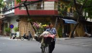 A street vendor selling flowers crosses the street with her bicycle in the old district of Hanoi on July 20, 2020. AFP / Nhac Nguyen 