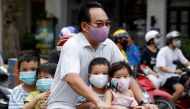 A man and his children, all wearing protective masks, ride a bicycle on a street during the coronavirus disease (COVID-19) outbreak, in Hanoi, Vietnam July 27, 2020. REUTERS/Kham