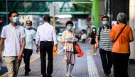 Pedestrians wear face masks in the Kowloon-side Sham Shui Po district of Hong Kong in the early morning of July 29, 2020, as new social distancing measures come into effect which include having to wear masks in public, to combat a new wave of coronavirus 