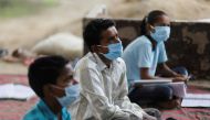 FILE PHOTO: Students of 9th class from a slum area, who do not have access to internet facilities and miss their online lessons, attend an open-air class taken by Satyendra Pal, a college student, after authorities closed all schools in March following th