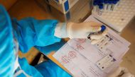 A medical specialist wearing a protective suit pours droplets of blood, collected from people who have returned from Da Nang, onto a test kit for coronavirus disease (COVID-19) at a rapid testing center outside Hanoi, Vietnam July 30, 2020. REUTERS/Kham