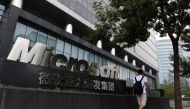 This file photo taken on July 31, 2014 shows a man walking past a Microsoft sign outside a Microsoft office building in Beijing. / AFP / Greg Baker