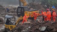 Rescue workers look for survivors at the site of a landslide during heavy rains in Idukki.