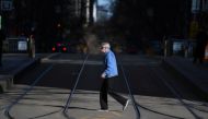 A pedestrian wearing a face mask crosses an empty street as the city operates under lockdown in response to an outbreak of the coronavirus disease (COVID-19) in Melbourne, Australia, August 18, 2020. AAP Image/James Ross via REUTERS 