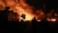 Migrants leave as a fire burns in the Moria camp on the island of Lesbos on September 9, 2020. / AFP / Manolis LAGOUTARIS